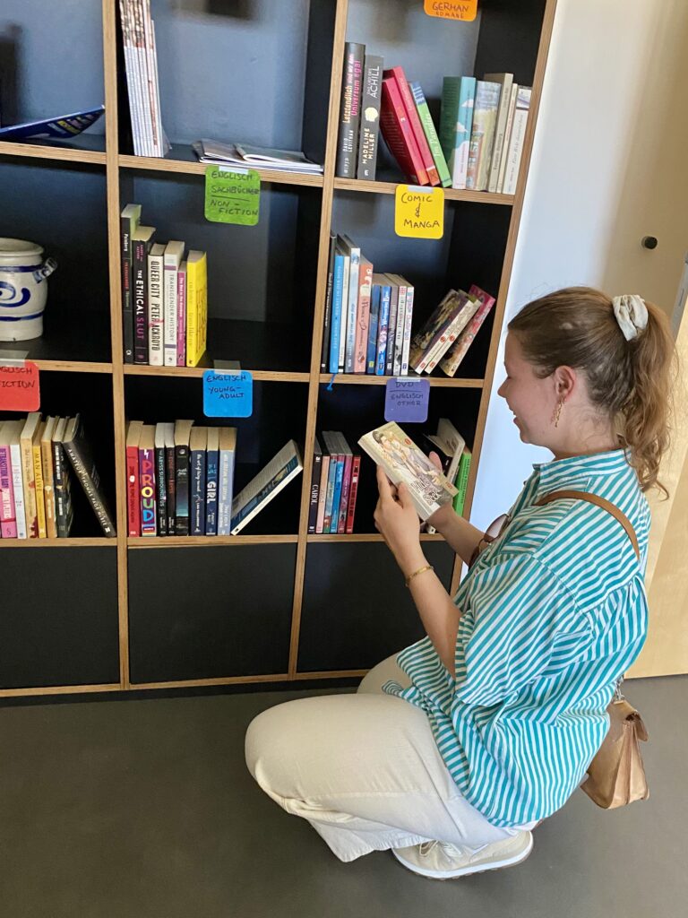 Print Chefredakteurin Marie Linn Lohmann beim Stöbern durch das Bücherregal